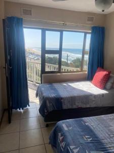 a bedroom with two beds and a large window at Umdloti Cabanas 32 Triplex in Umdloti