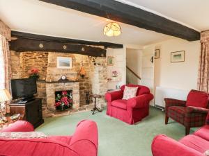 a living room with red chairs and a stone fireplace at Lower Farm Cottage in Weymouth