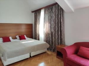 een slaapkamer met een bed en een rode bank bij Hotel Ambasador in Podgorica