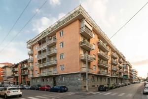un grande edificio in mattoni con auto parcheggiate sulla strada di Parco Paradiso & MM Marche Family Apartment a Torino