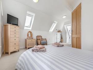 a white bedroom with a large bed and a tv at Primrose Cottage in Poundstock