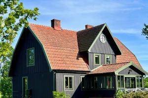 una gran casa negra con techo rojo en Exclusive Castle Gatehouse Österlen, en Tomelilla
