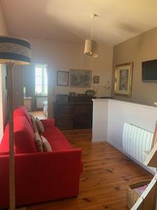 un soggiorno con divano rosso e tavolo di La maison de Fanny a Jarnioux