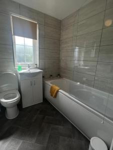 La salle de bains est pourvue d'une baignoire, de toilettes et d'un lavabo. dans l'établissement CAPRI 13 SA- Nice ’n’ New, close to Uni and M1/J23, à Loughborough