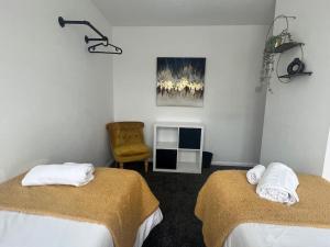 a hotel room with two beds and a chair at CAPRI 13 SA's 3 bedroom home, close to Loughborough University and M1 in Loughborough