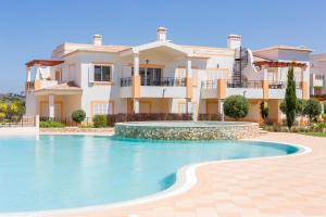 a villa with a swimming pool in front of a house at NAU Salema Beach Village in Salema