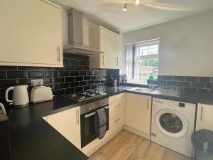 a kitchen with white cabinets and a washer and dryer at CAPRI 13 SA- Nice ’n’ New, close to Uni and M1/J23 in Loughborough