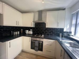 a kitchen with white cabinets and a sink at CAPRI 13 SA's 3 bedroom home, close to Loughborough University and M1 in Loughborough