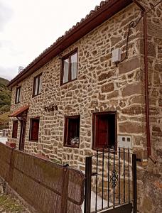 una casa de piedra con una valla delante de ella en Las Monas Casa Rural 