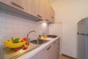 a kitchen with a sink and a bowl of fruit at Residenza Puerto Do Sol in Lignano Sabbiadoro