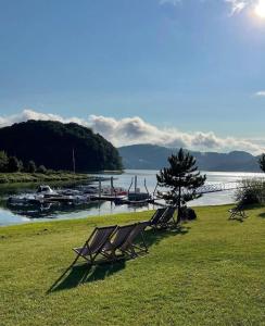 un gruppo di sedie seduti sull'erba vicino a un fiume di L57_resort a Gródek Nad Dunajcem