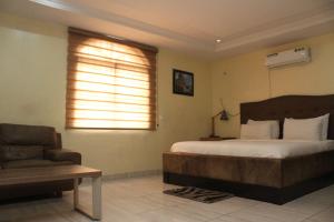 a bedroom with a bed and a couch and a window at MITOS LUXURY SUITES -Somosu in Lagos