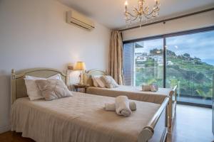 dwa łóżka w pokoju z dużym oknem w obiekcie Gold Villa w Funchal