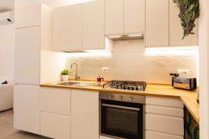 eine Küche mit weißen Schränken und einem Herd und einer Spüle in der Unterkunft Brenta Top Floor - MM3 Yellow Line in Mailand