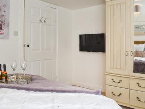 a bedroom with a bed and a tv and a dresser at The Firs Lodge in Buckland St Mary