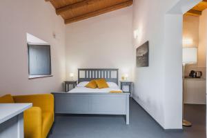 a bedroom with a bed and a yellow chair at Terrazze dell'Etna - Country rooms and apartments in Randazzo