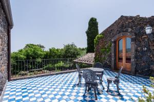 eine Terrasse mit 2 Stühlen und einem Tisch auf einem Fliesenboden in der Unterkunft Terrazze dell'Etna - Country rooms and apartments in Randazzo