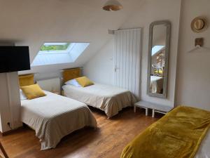 sypialnia z 2 łóżkami i dużym lustrem w obiekcie Grande Chambre Familiale JAUNE Tout Bonnement Bien w mieście Putot-en-Auge