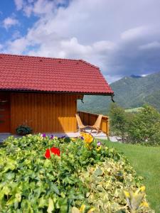 a house with a chair and flowers in front of it at POČITNIŠKA HIŠKA LASTOVKA in Podvolovljek
