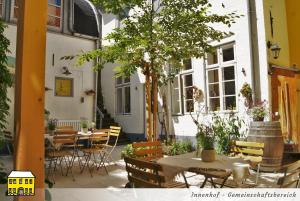 un patio con mesas, sillas y un árbol en Das Gelbe Haus - Drei besondere Ferienwohnungen en Flensburg