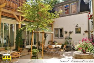 un patio con mesa, sillas y un árbol en Das Gelbe Haus - Drei besondere Ferienwohnungen en Flensburg