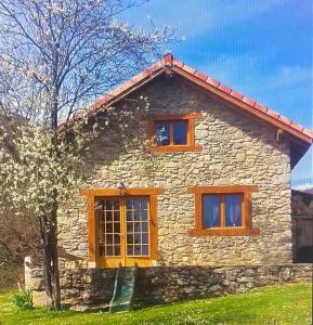 una casa de piedra con 3 ventanas y un árbol en Gîte Mourtis, en Nistos