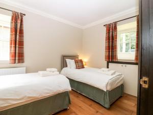 two beds in a room with two windows at The Old Laundry Cottage in Perth