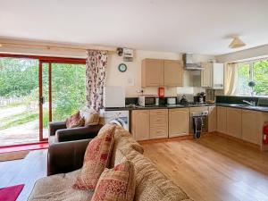 a living room with a couch and a kitchen at Woodside Fishery - Kingfisher in Cleobury Mortimer