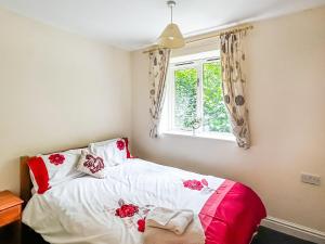 Un dormitorio con una cama con sábanas rojas y blancas y una ventana. en Woodside Fishery - Kingfisher, en Cleobury Mortimer