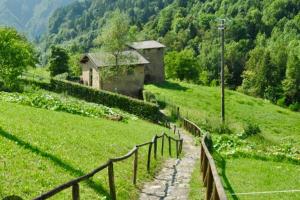 a small building on a grassy hill with a fence at Appartamento panoramico Casa Gerro in Averara