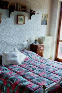 a bedroom with a bed with a quilt and a table at Appartamento panoramico Casa Gerro in Averara