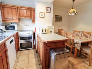 a kitchen with wooden cabinets and a table with a counter top at 7 Stybarrow Terrace in Penrith