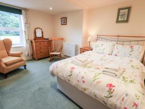 a bedroom with a bed and a chair and a window at 7 Stybarrow Terrace in Penrith