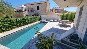einen Pool mit Stühlen, einem Tisch und einem Haus in der Unterkunft Delta House - Alfa apartment in Zadar