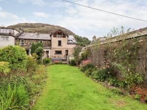 a garden with a house and a hill in the background at 7 Stybarrow Terrace in Penrith