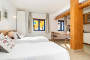 a hotel room with two beds and a desk at Apartamentos Rossio Mar in Albufeira