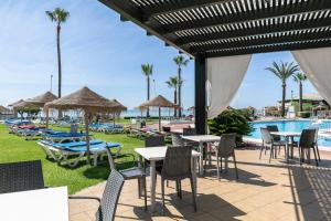 eine Terrasse mit Tischen und Stühlen neben einem Pool in der Unterkunft Sol Guadalmar in Málaga