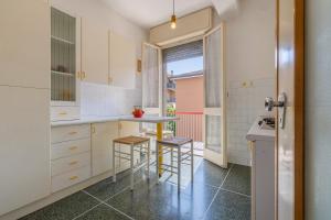 a kitchen with white cabinets and stools in it at Bologna Rimesse & Ospedale Sant'Orsola Apartment in Bologna