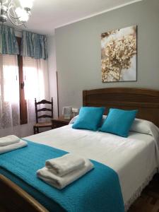 a bedroom with a large bed with blue pillows at Apartamento Casa Belén Arriondas in Arriondas
