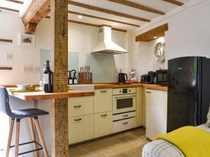 a kitchen with white cabinets and a black refrigerator at The Telephone Box At The Old Post Office in North Perrott