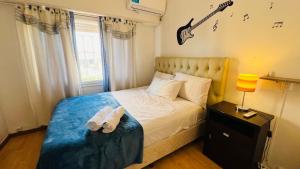 1 dormitorio con 1 cama con una guitarra en la pared en Excelente Casa c/ Pileta Cerca del Centro en Villa Carlos Paz