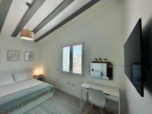 a bedroom with a bed and a desk and a tv at Villa Noga Rooms in Selargius
