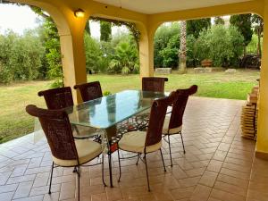 une table et des chaises en verre sur la terrasse dans l'établissement Villa Pientime - natura e mare, à Formia