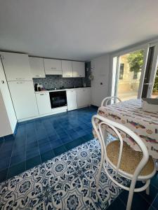 - une cuisine avec des placards blancs, une table et des chaises dans l'établissement Il Viandante sul Mare, à Salerne