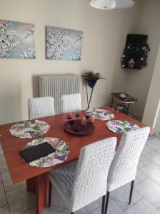 uma mesa de jantar com cadeiras brancas e uma mesa de madeira com uma toalha de mesa em Nikos Apartments em Amarinthos