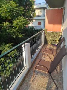 Dois bancos sentados numa varanda com um corrimão em Nikos Apartments em Amarinthos