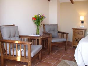 um quarto com duas cadeiras e uma mesa com um vaso de flores em Apartamento San Anton em La Iruela