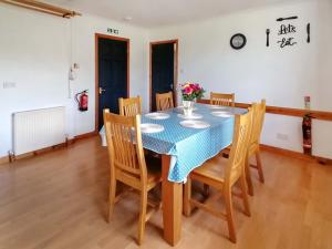 a dining room with a blue table and chairs at Maari in Trumisgarry