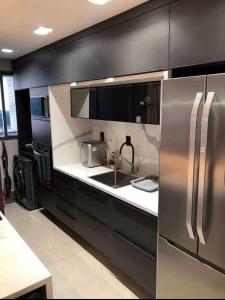 uma cozinha com armários pretos e um frigorífico de aço inoxidável em Apartamento moderno em João Pessoa
