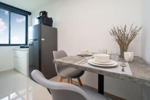 Il comprend une cuisine équipée d'une table, de chaises et d'un réfrigérateur. dans l'établissement New Studio with Disability-Friendly Features, Central Hill View A6-724 A, à Ban Ket Ho